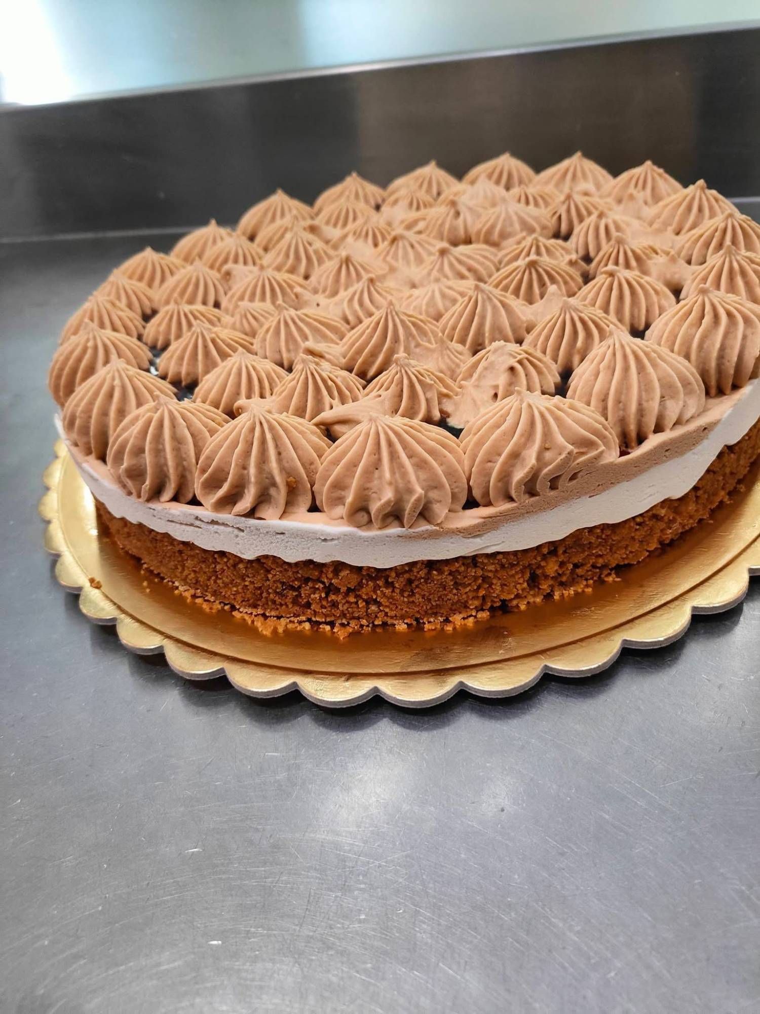 Cheesecake su base di biscotto, coperta di ciuffi di crema al cioccolato
